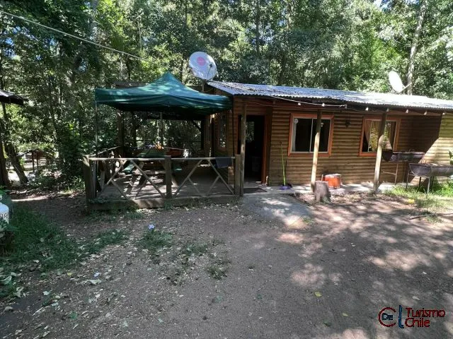 Fachada exterior de cabaña de madera con jardín en Las Vertientes Salto del Laja